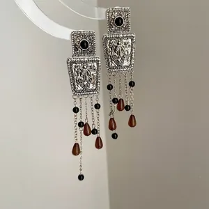 Detailed macro shot of vintage silver square earrings with intricate floral carving