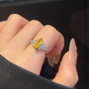 Close-up view of a silver open ring with a marquise yellow zircon on a finger.