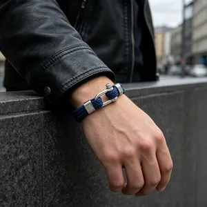 Gros plan d'un bracelet tressé bleu marine avec fermoir à manille argenté au poignet.