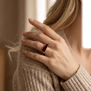 Bague rétro en acier inoxydable avec incrustation de résine rouge portée par un modèle.