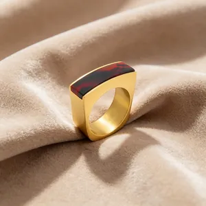 Gros plan d'une bague carrée vintage avec résine rouge sur velours beige