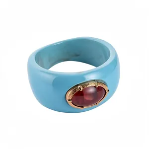 Brazalete ancho de resina azul claro jaspeada con una piedra roja ovalada central