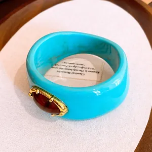 Primer plano del brazalete de resina jaspeada turquesa con una gran piedra de ámbar