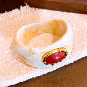 Detalle de cerca de un brazalete de resina jaspeada con un cabujón rojo vintage