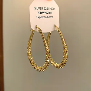 Detailansicht der goldenen Tropfenohrringe mit einem gewebten Oberflächenmuster
