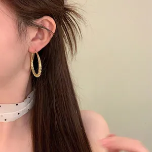 Detailaufnahme eines eleganten, goldenen Tropfenohrrings, getragen von einem asiatischen Model
