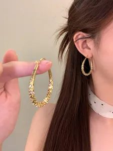 Detailansicht der goldenen Wassertropfen-Ohrringe mit strukturierter Oberfläche und Model.