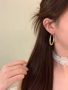 Elegante Vintage-Gold-Ohrringe in Tropfenform mit Textur, am Ohr des Models präsentiert.
