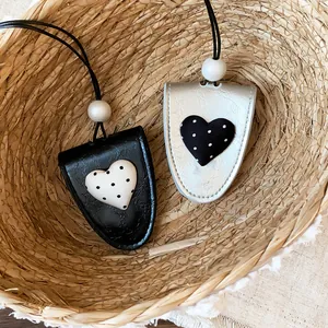 Nahaufnahme von stylischen Leder-Sonnenbrillen-Clips mit Polka-Dot-Herz in einem Korb