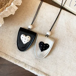 Nahaufnahme von Leder-Sonnenbrillenclips mit gepunktetem Herz in Schwarz und Silber.