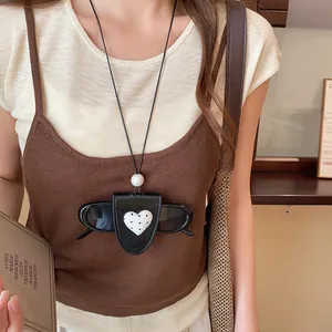 Detail eines Leder-Sonnenbrillenclips mit Herzmuster, getragen als stylische Kette