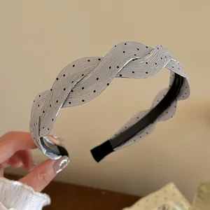 Primer plano detallado de una diadema de satén trenzada plateada con lunares negros chic