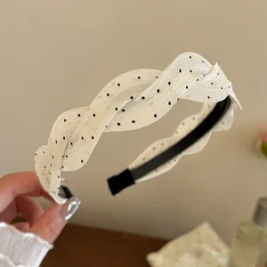 Vista detallada de una diadema de satén blanco con lunares y una elegante textura de seda