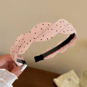 Detalle de una diadema de satén rosa trenzada con elegantes lunares negros clásicos