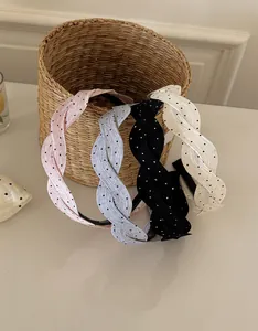 Detalle de cuatro diademas trenzadas de satén con lunares de colores para el cabello