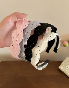 Primer plano de cuatro diademas de satén trenzado con lunares en colores rosa, gris y blanco.