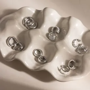 Luxe collectie zilveren roestvrijstalen oormanchetten op een witte keramische schaal