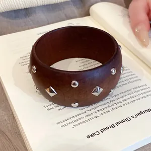 Dunkelbrauner Holzarmreif im Ethno-Stil mit silberfarbenen Nieten für einen Vintage-Look.