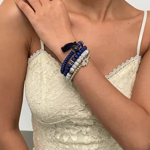 Close-up of four-piece beaded bracelet set with Hamsa hand charm and tassel detail
