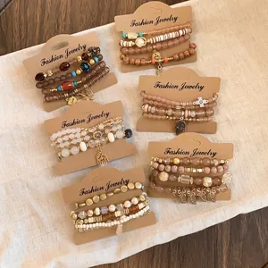 Bohemian multi-layer beaded bracelet set with hamsa hand and leaf charms on display cards.