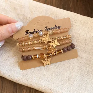 Detail of four-piece beaded bracelet set with gold butterfly charms and amber beads