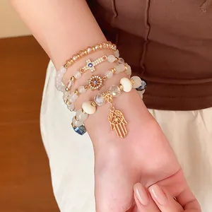 Stylish bohemian beaded bracelet set featuring Hamsa hand and cross charms on wrist