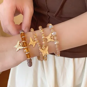 Close-up of stylish gold butterfly charm beaded bracelet set on model's slender wrist