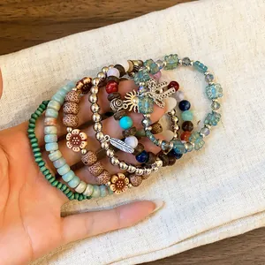 Detail view of bohemian multilayer beaded bracelets with sun and feather charms.
