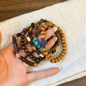 Close-up of bohemian layered beaded bracelet set with wooden cross on linen background