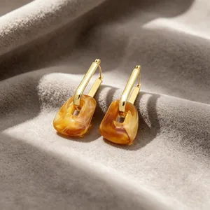 Detailed view of minimalist gold-plated earrings with amber marbled resin square drops