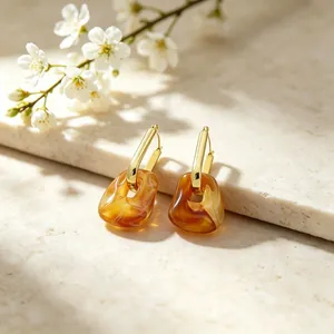 Close-up of gold geometric paperclip earrings with brown marbled resin pendant detail