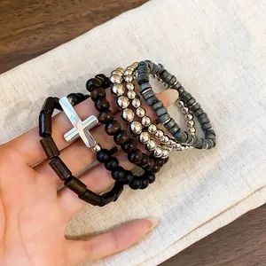 Close-up detail of Bohemian layered bracelets with wooden beads and silver cross charm
