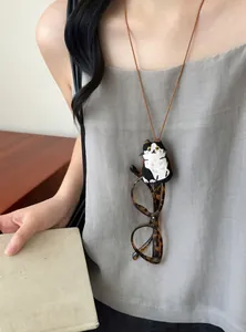 Detail van een schattige geborduurde kattenpop brillenhouder ketting gedragen door een model