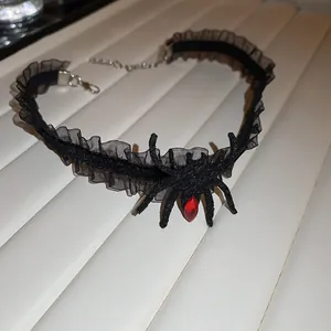 Detailed shot of a black lace Gothic choker with a spider pendant and red gemstone