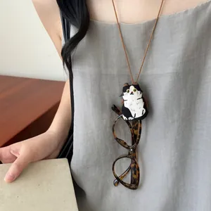 Close-up detail van een schattige geborduurde kattenpluche brilhouderketting op grijs linnen