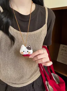Handgemaakte pluchen kattenbedelketting gedragen door een model in casual kleding