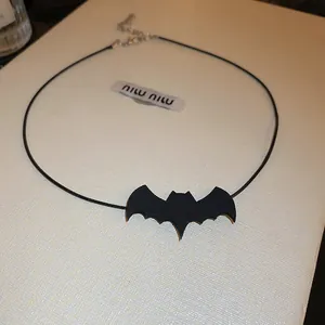 Detailed macro shot of a black bat-shaped Halloween choker necklace on textured box