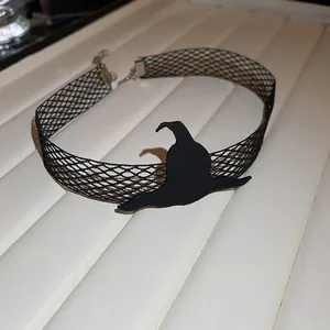 Detailed view of black fishnet Halloween choker featuring a witch hat silhouette charm