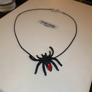 Detailed view of a black Halloween spider necklace with a sparkling red gem
