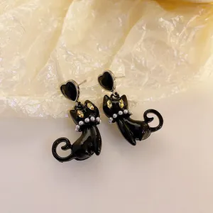 Detailed macro view of black cat earrings with heart studs and pearl collar