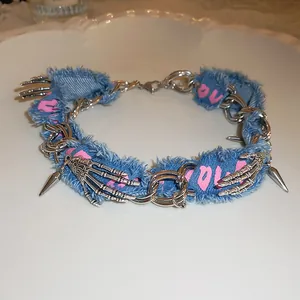 Detail of punk denim choker with silver skeleton hands and pink love print