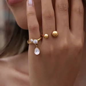 Close-up detail of a gold titanium steel ring with a dangling waterdrop zircon pendant.