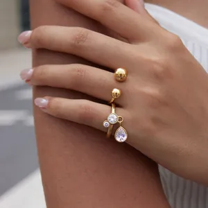 Detailed close-up of a gold titanium steel ring featuring a dangling teardrop zircon.