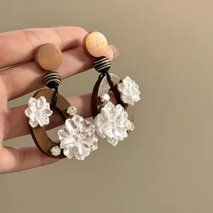 Nahaufnahme von eleganten handgefertigten Harzblumen-Ohrringen mit dunklem Holzboden