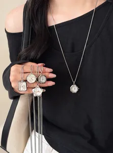 Detailansicht verschiedener geometrischer Taschenuhr-Anhänger-Halsketten an einem Modell