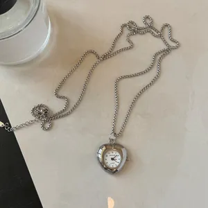 Detail view of heart-shaped quartz watch pendant necklace in silver