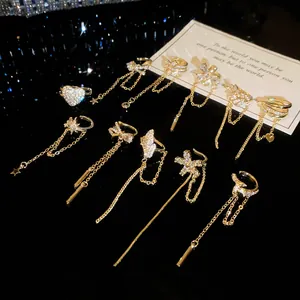 Detail view of sparkling zircon flower and tassel ear cuffs on a dark reflective surface.