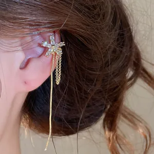 Close-up detail of an elegant zircon flower ear cuff featuring long golden tassels worn on ear