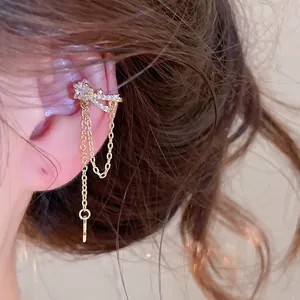Close-up detail of a delicate gold zircon star ear cuff with elegant dangling tassels