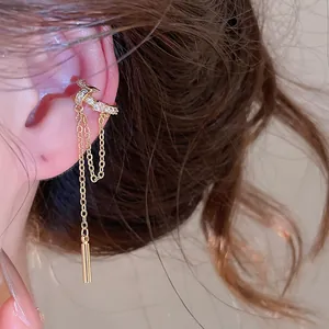 Detailed view of a gold-finish zircon tassel ear cuff worn on the ear cartilage.